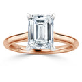Emerald-cut diamond solitaire ring with a rose gold band and four-prong setting on a white background.