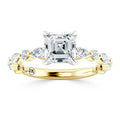 Gold ring with an emerald-cut center diamond and oval side diamonds on a twisted band.