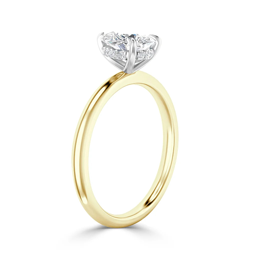 A gold engagement ring with a round diamond solitaire set in a white gold prong setting against a white background.