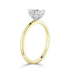 A gold engagement ring with a round diamond solitaire set in a white gold prong setting against a white background.
