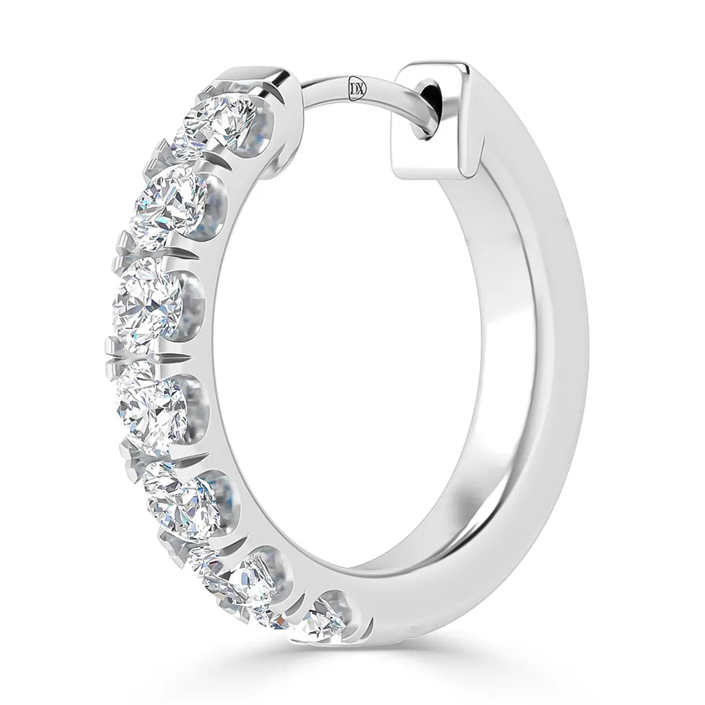 Silver hoop earring with seven round, sparkling white gemstones set along the front half of the hoop.