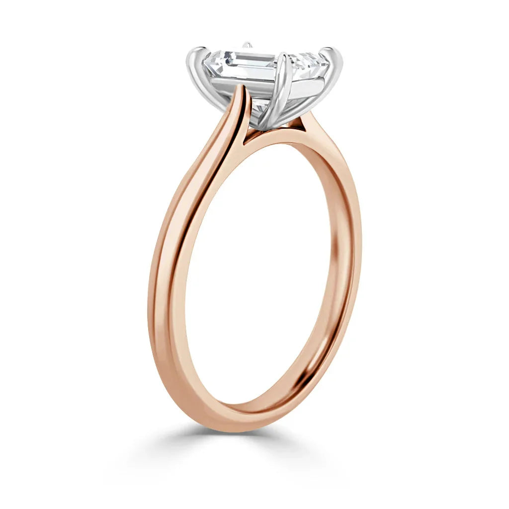A rose gold ring with a thin band and a prong-set emerald-cut diamond solitaire in a white gold setting.