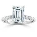 Emerald-cut diamond ring with a diamond-studded band set in white metal on a white background.