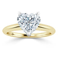 Heart-shaped diamond ring with a yellow gold band and prong setting on a white background.