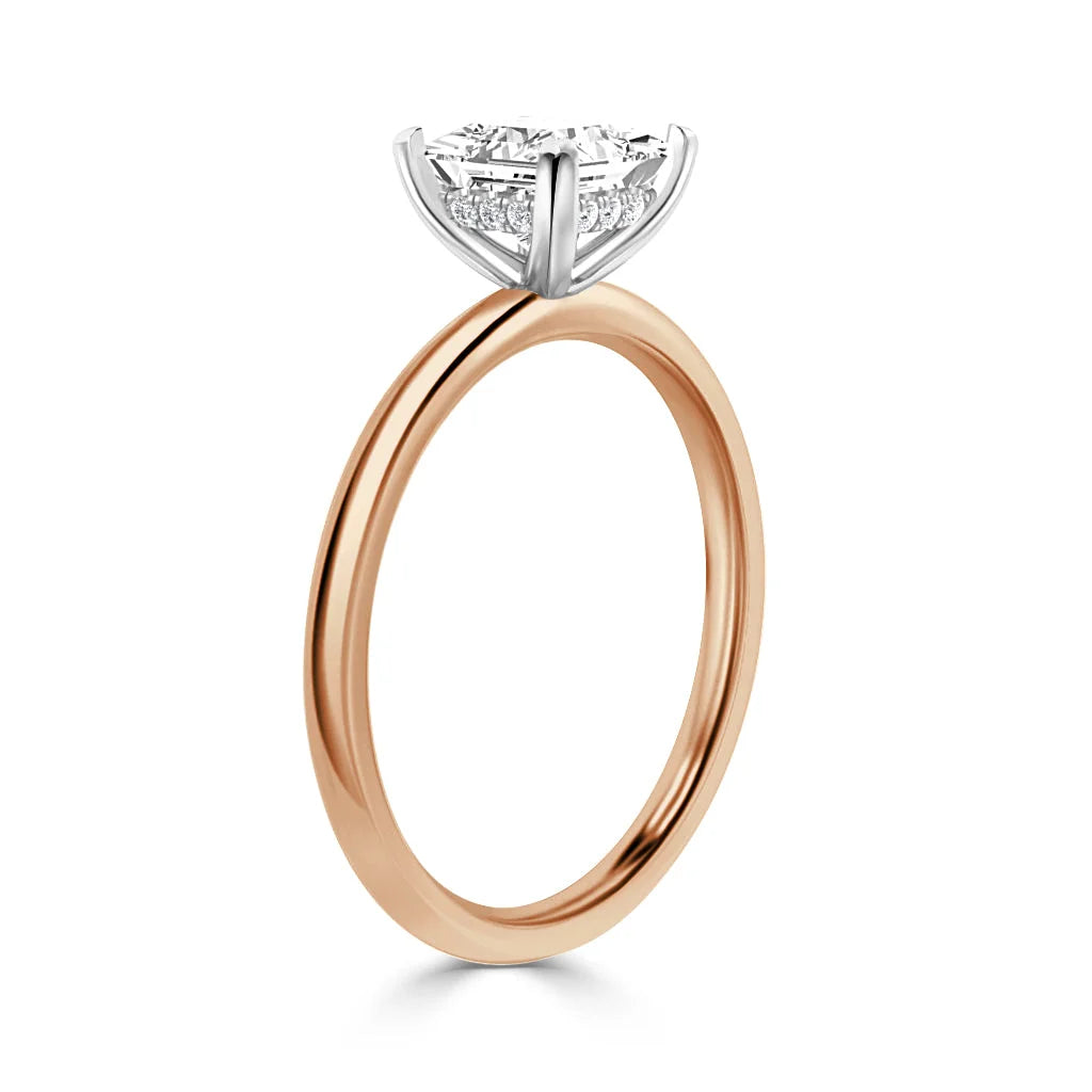 A gold ring with a round, prong-set diamond solitaire in a white gold setting against a white background.