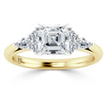 Gold band ring with a large square diamond center flanked by two round and two pear-shaped side diamonds.