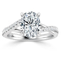 Oval diamond solitaire ring with split shank band accented by small round diamonds on a white background.
