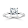 A solitaire ring with a princess-cut diamond set on a thin, polished white metal band.