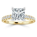 Gold ring with a large square diamond center and smaller diamonds set along the band, on a white background.