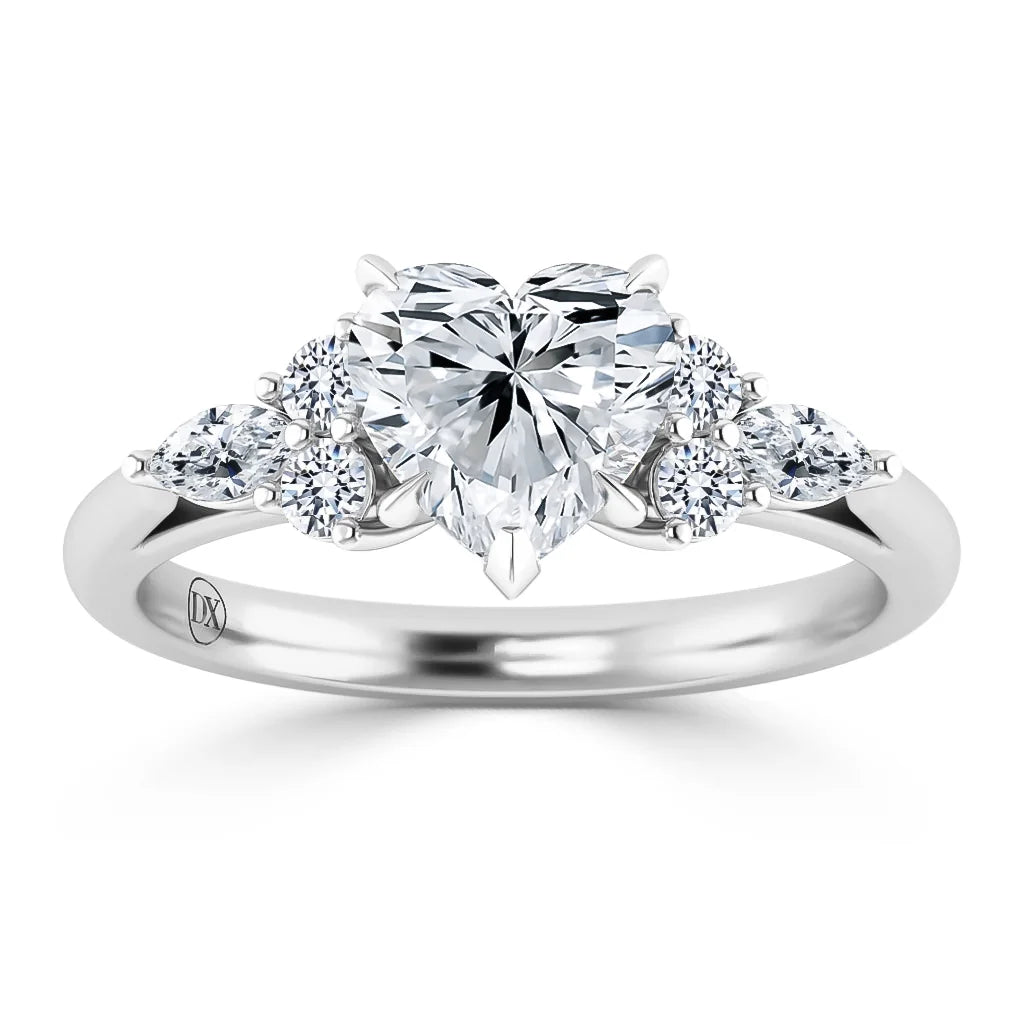 A silver ring with a heart-shaped diamond center, flanked by smaller round and pear-shaped diamonds.
