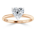 A gold band ring with a heart-shaped diamond solitaire set in a minimalist prong setting.