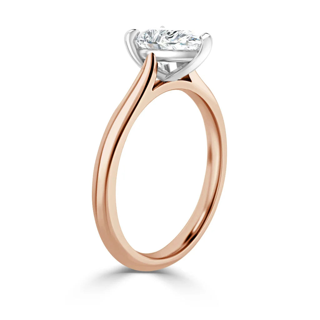 Rose gold solitaire ring with a round diamond set in a white gold prong setting, viewed from the side.