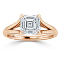 A rose gold ring with a square, emerald-cut diamond held by four prongs on a split shank band.