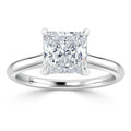 A solitaire ring with a square princess-cut diamond set on a simple, polished white gold band.