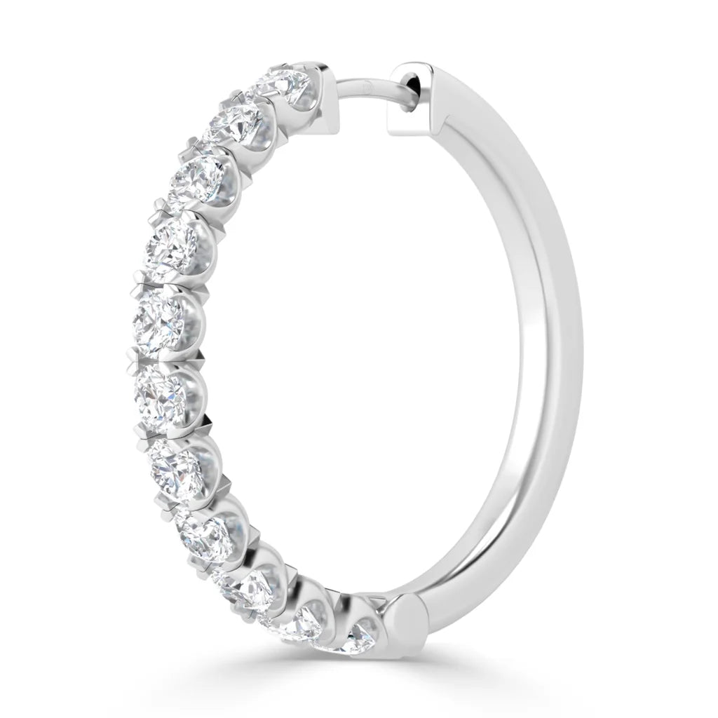 A silver hoop earring with round, prong-set white diamonds lined along half of the outer edge.
