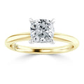 A gold band ring with a cushion-cut diamond solitaire set in a four-prong white gold or platinum setting.