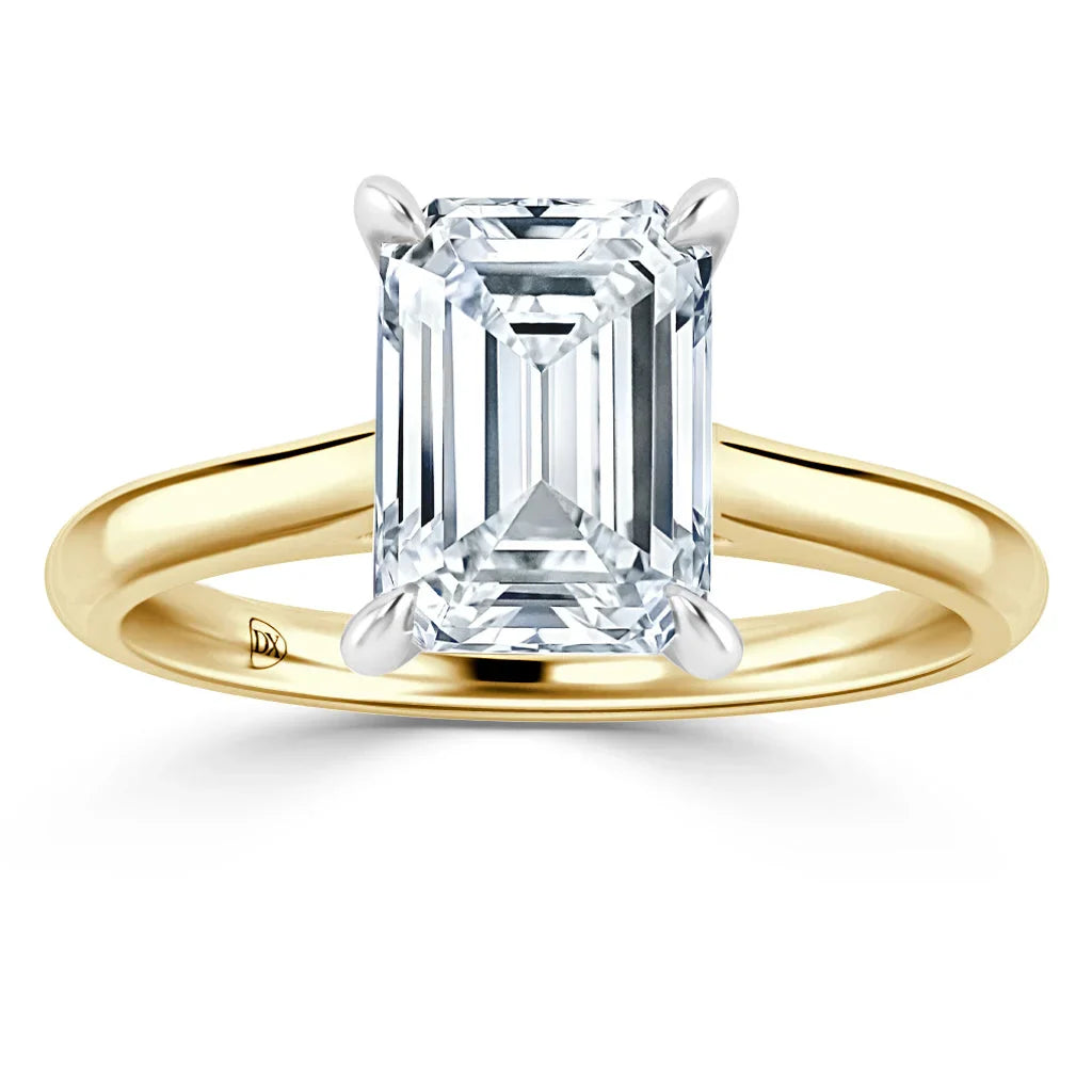 Emerald-cut diamond solitaire ring with a yellow gold band and four-prong white gold setting.