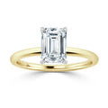 A gold band ring featuring a large emerald-cut clear diamond held by four prongs on a plain setting.