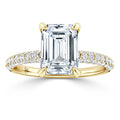 Gold ring with an emerald-cut diamond center and a band encrusted with small round diamonds.