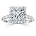 A square-cut diamond ring with a double halo and diamond-studded band set in white metal.