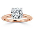 A cushion-cut diamond solitaire on a rose gold band with four prongs securing the gemstone.