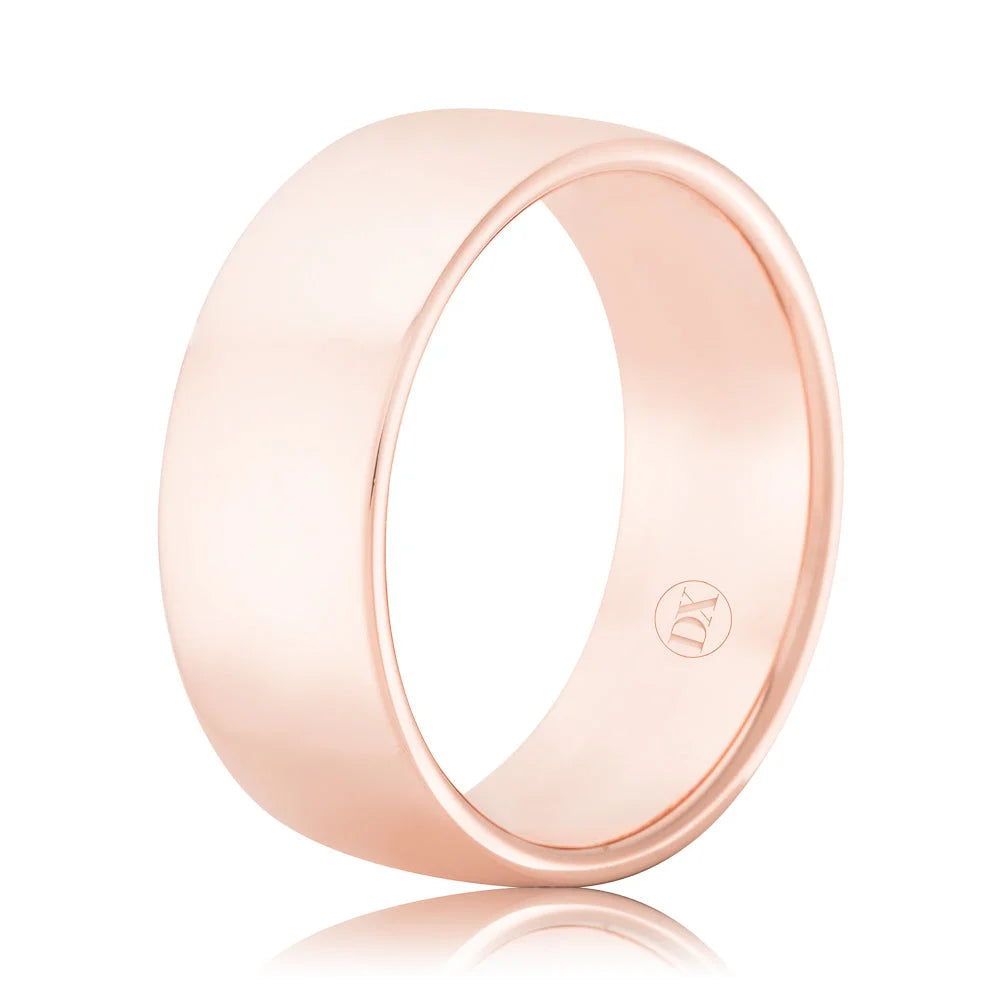 A simple, wide rose gold ring with a smooth, polished surface and a small engraved logo inside.