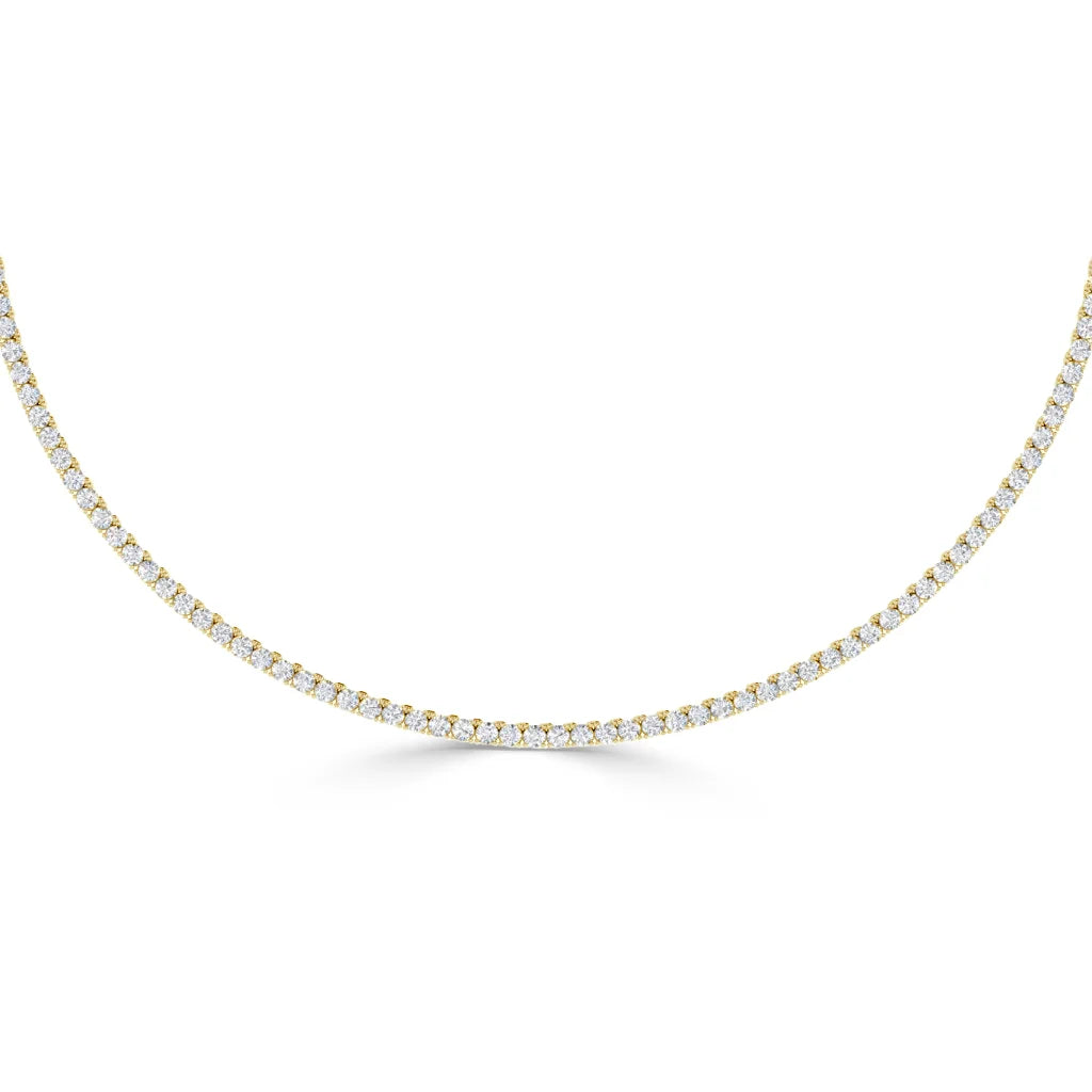 A gold tennis necklace with closely set round white diamonds, displayed on a plain white background.
