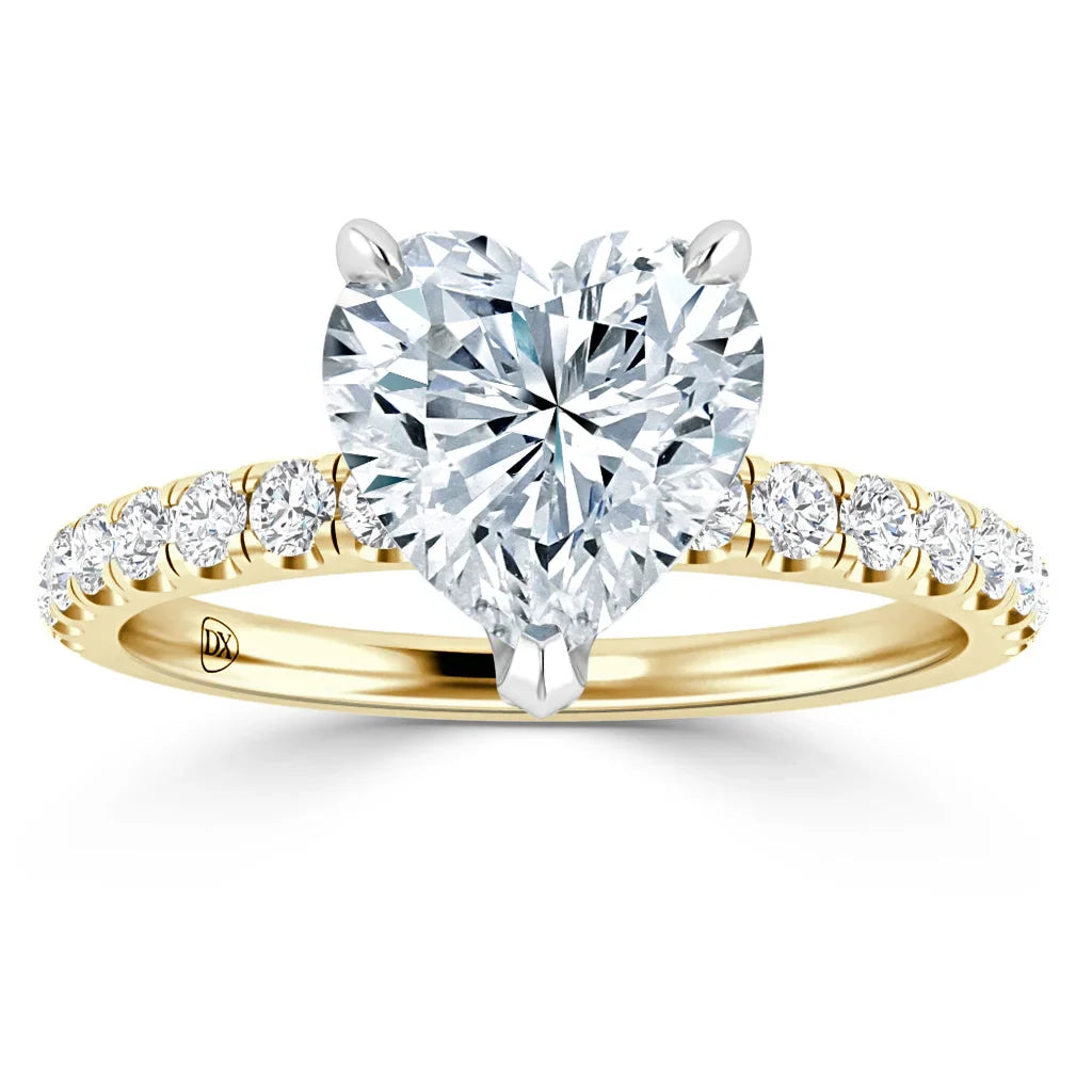 Heart-shaped diamond ring with a gold band and smaller diamonds set along the band, on a white background.