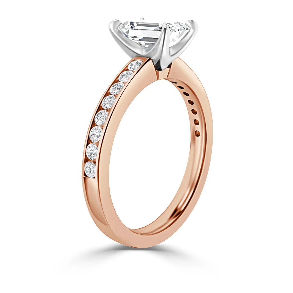 Rose gold ring with a row of round diamonds and a large emerald-cut center stone in a white gold prong setting.