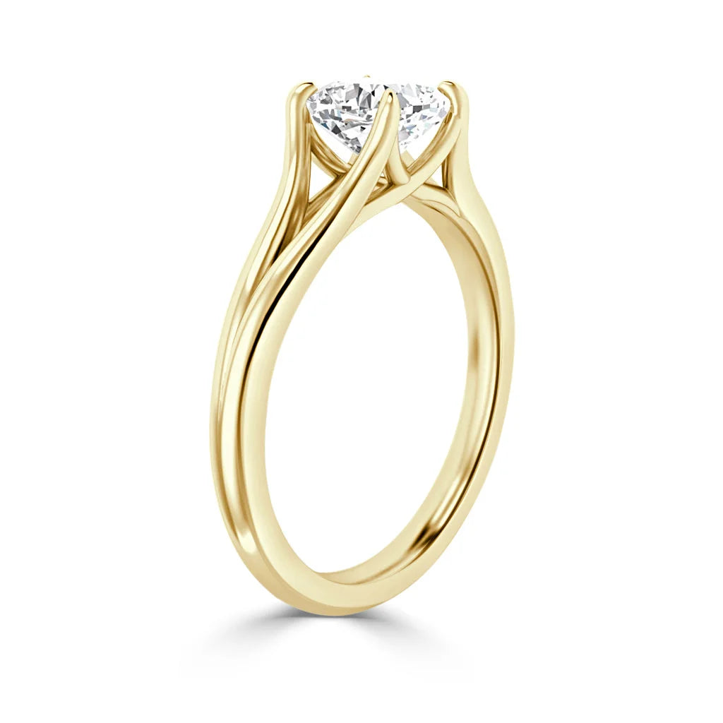 Gold engagement ring with a round diamond solitaire in a twisted prong setting, viewed from the side.