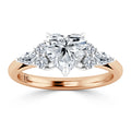 Rose gold ring with a heart-shaped center diamond and smaller round and marquise diamonds on each side.