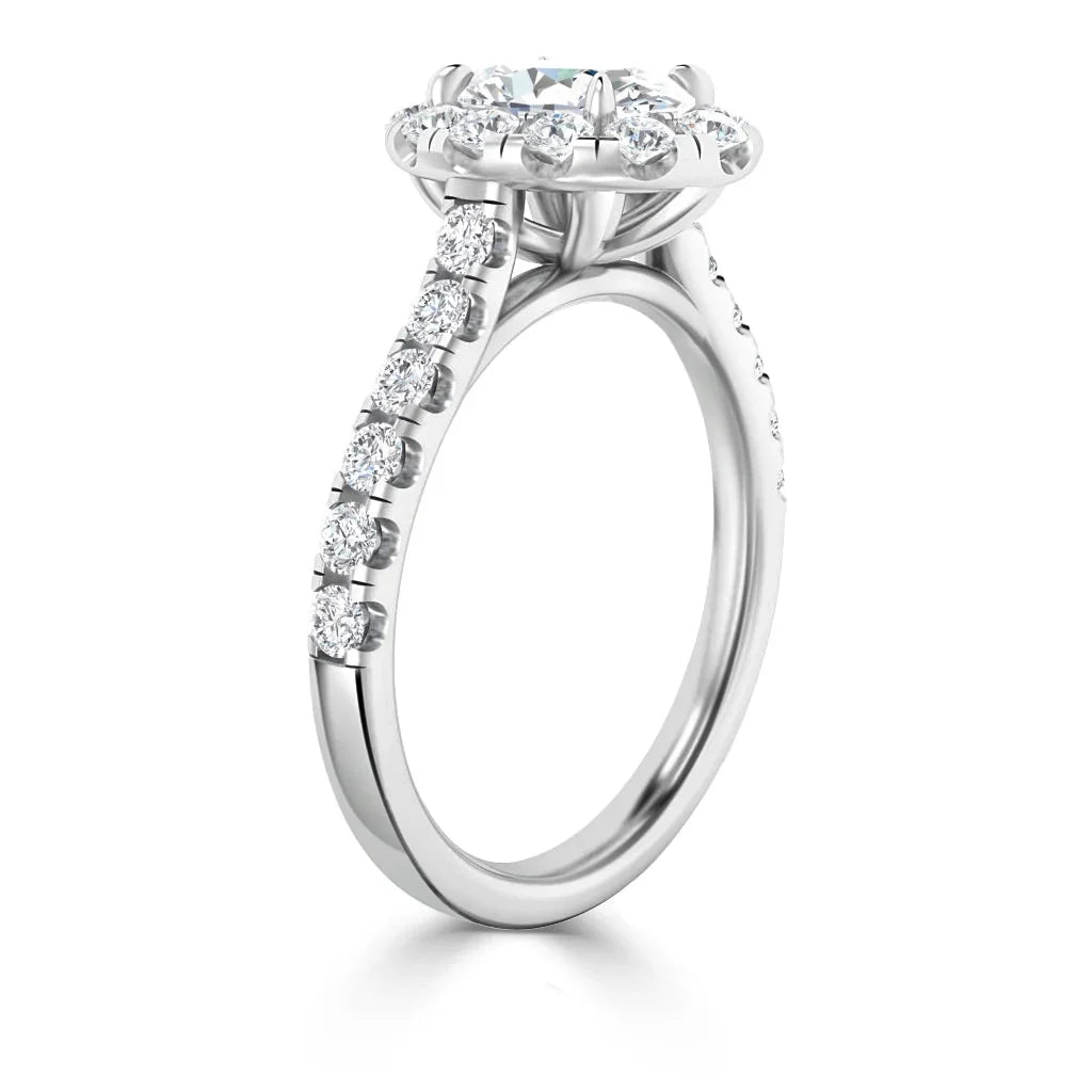 A white gold ring with a round halo diamond setting and diamonds along the band, viewed from the side.