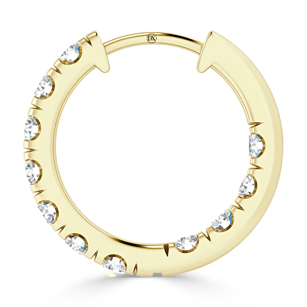 A gold hoop earring adorned with evenly spaced round white gemstones along its outer edge.