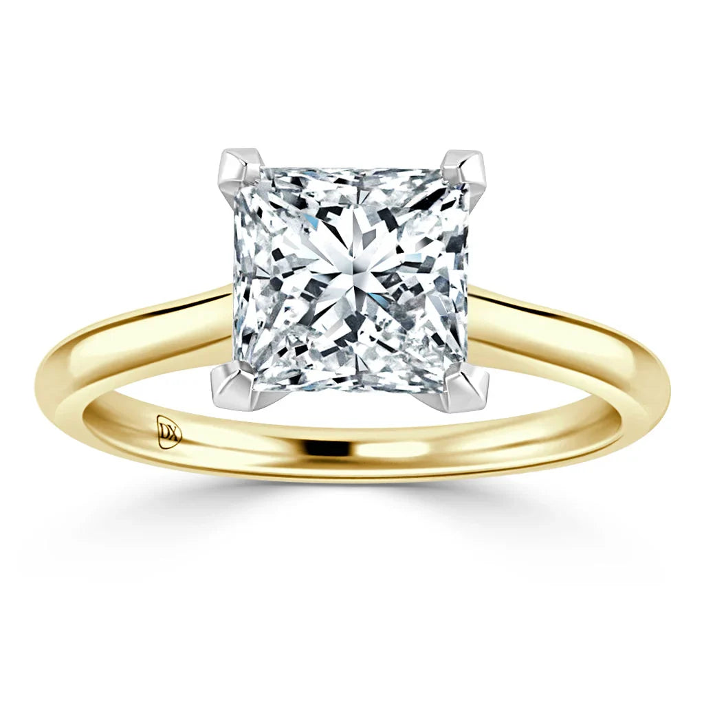 Gold ring with a large princess-cut diamond solitaire set in four prongs on a simple band, white background.