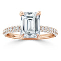 Rose gold ring with a large emerald-cut diamond and a band encrusted with small round diamonds.
