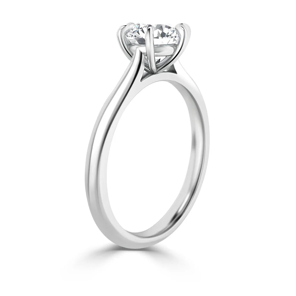 A solitaire diamond engagement ring with a thin, plain silver band and a prong setting, viewed from the side.