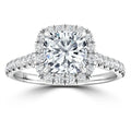 A cushion-cut diamond ring with a halo and pavé diamond band on a white gold setting.