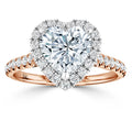 A heart-shaped diamond ring with a halo of smaller diamonds on a rose gold band with diamond accents.