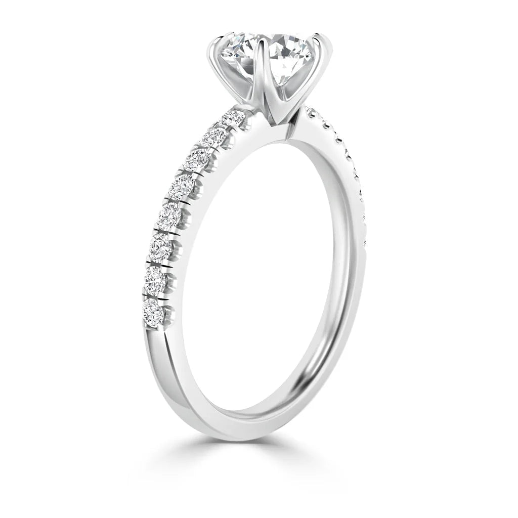 A white gold ring with a large solitaire diamond and smaller diamonds set along the band.