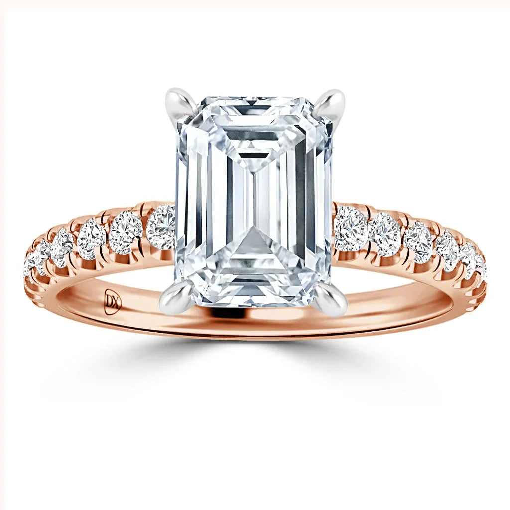 Rose gold ring with emerald-cut diamond center and round diamonds along the band, viewed from above.