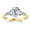 A gold ring with a pear-shaped diamond center, flanked by two smaller round diamonds on each side.