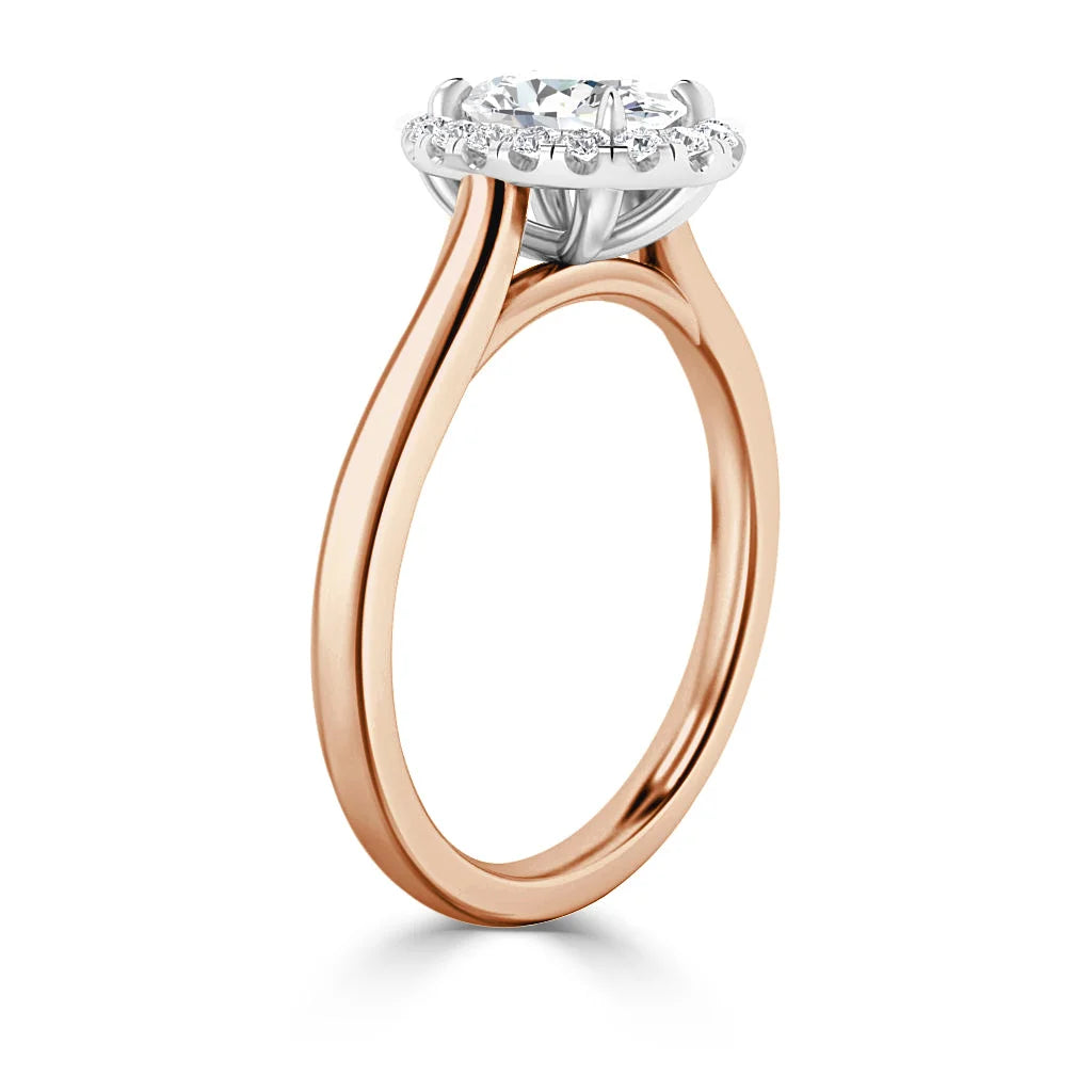 Rose gold engagement ring with a round diamond halo setting and slim, split shank band.