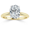 Oval-cut diamond solitaire ring with a yellow gold band and four prongs, shown on a white background.