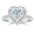 Heart-shaped diamond ring with halo and pavé band set in white metal, sparkling brightly.
