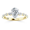 A gold ring with a pear-shaped diamond center and round diamonds set along the twisted band.
