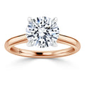 A round-cut diamond solitaire ring with a rose gold band and four prongs on a white background.