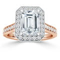 Emerald-cut diamond ring with halo of smaller diamonds, rose gold band, and intricate side detailing.
