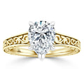Oval diamond solitaire ring with ornate gold band featuring intricate swirling engravings.