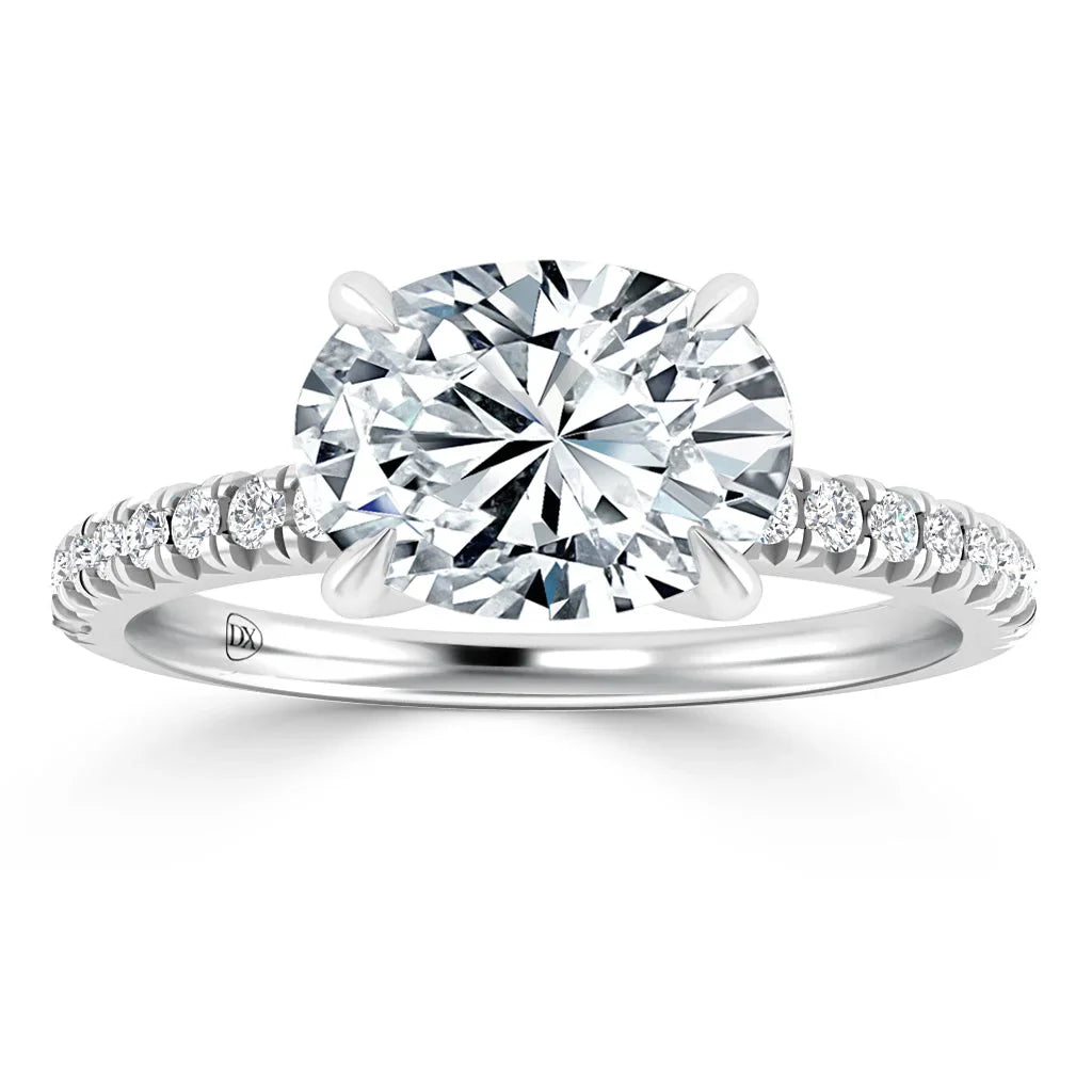 Oval diamond ring with a pavé band of small diamonds on a white metal setting, shown on a white background.