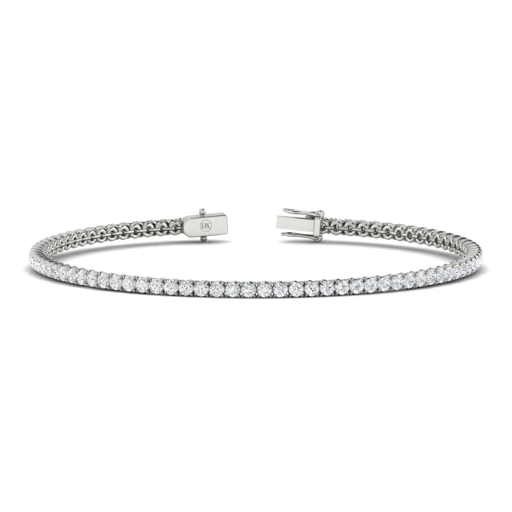 The Monica by DX Diamonds is a handcrafted platinum tennis bracelet featuring evenly spaced small diamonds, offering elegance and timelessness. This jewellery staple, displayed on a plain white background, includes a secure clasp for closure and is perfect for any occasion.
